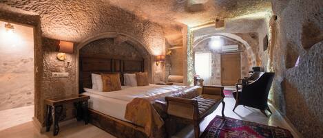 A stone-walled bedroom with a bed, wooden furniture, and a patterned rug.