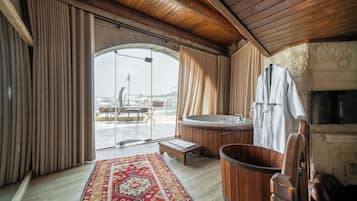 Una habitación con techo de madera, un ventanal amplio, bañera de hidromasaje y vistas a la ciudad.