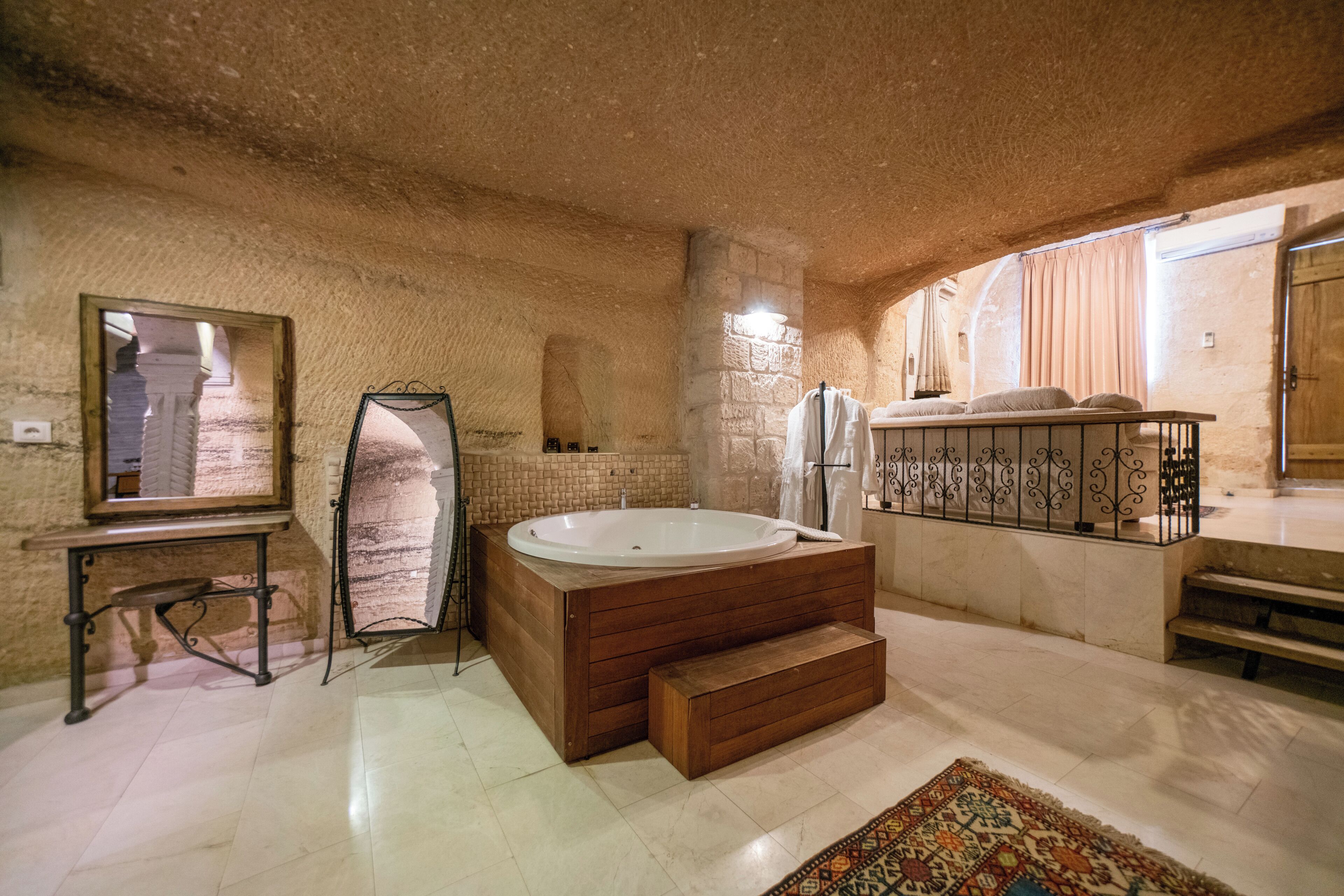 Un baño amplio con una bañera grande, un espejo y un banco de madera.
