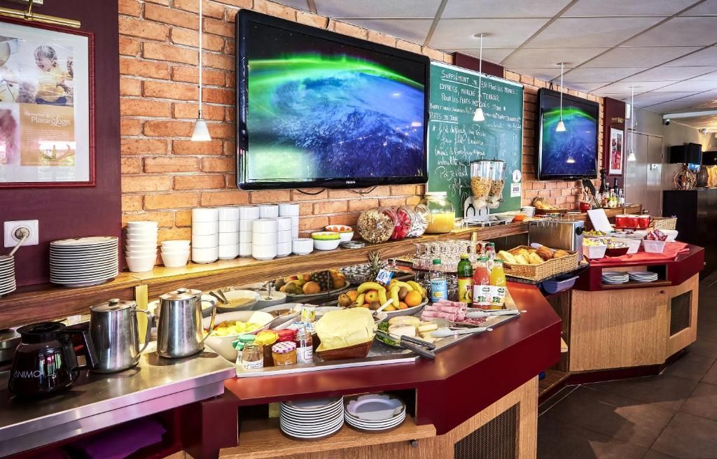 A breakfast buffet with various food items and a TV screen displaying a natural scene.