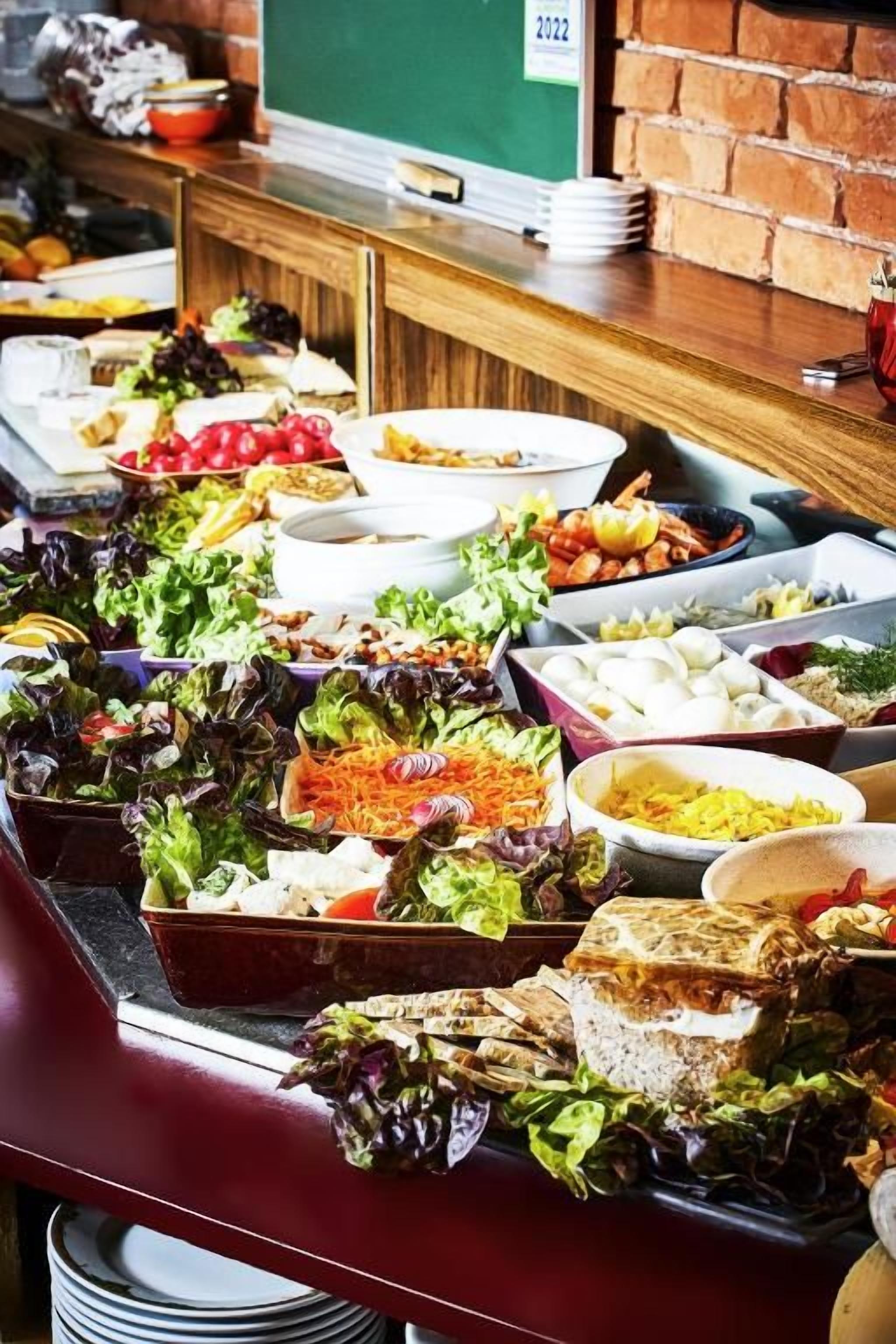 Un bufé con diversos alimentos, como ensaladas, sándwiches y otros platos.