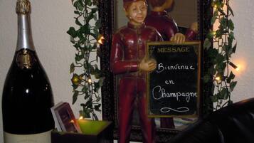 Una botella de champán Jacquesson & Fils, una figura decorativa sosteniendo un cartel y un espejo con adornos de hiedra.