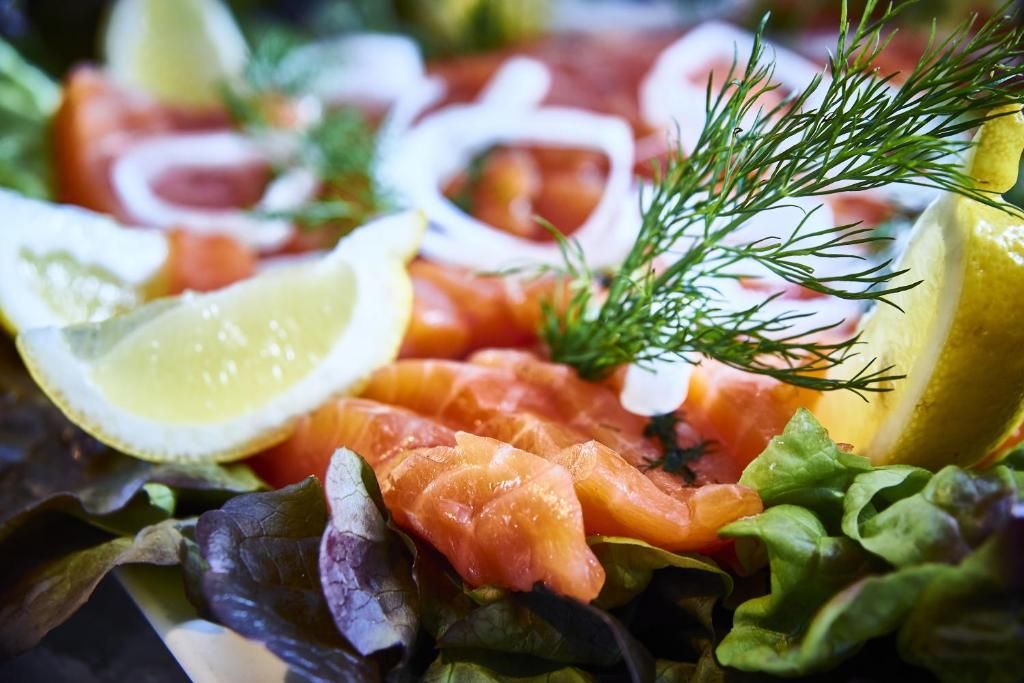 A close-up of a food platter with salmon, lemon slices, and dill.