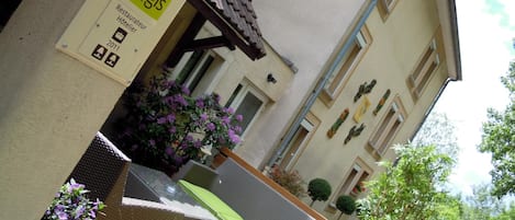 Exterior de un hotel con asientos al aire libre, un letrero que dice 'Logis' y vista de la calle.