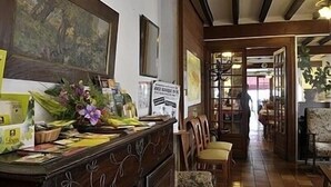 Una zona de recepción con un escritorio de madera, sillas y un cuadro grande en la pared.