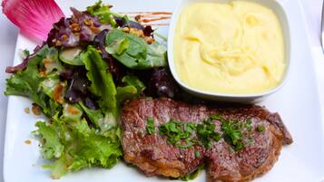 Une assiette avec un steak, une salade et une sauce crémeuse.