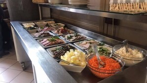 Un bufé con diversos alimentos, entre ellos, carnes en rodajas, verduras y un bol de zanahoria rallada.