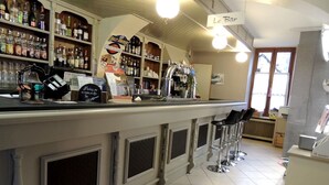 Zona de bar con mostrador, taburetes y estantes llenos de botellas.