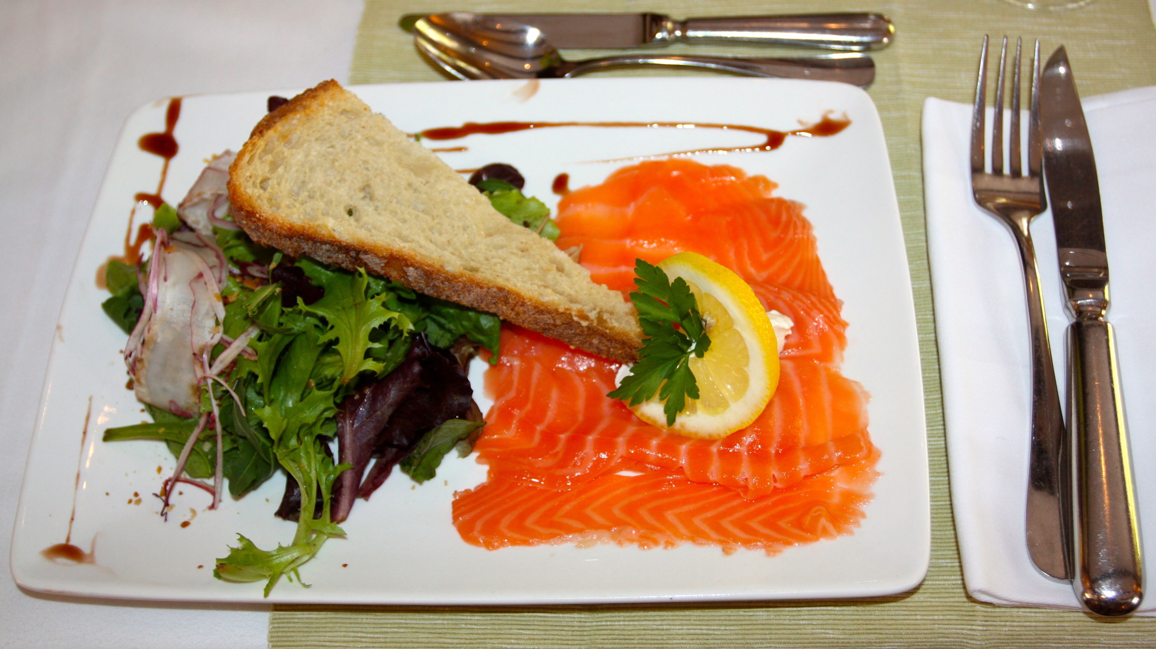 Un plato con salmón, pan y ensalada.