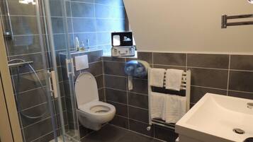 Un baño moderno con ducha envuelta en vidrio, inodoro blanco, lavamanos y toallero.