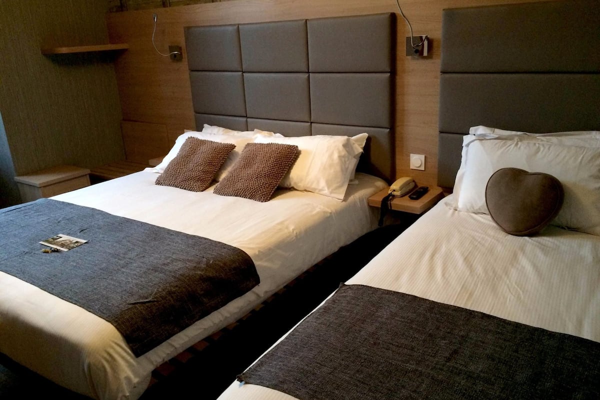 Ein Doppelbett mit Kopfteil, Nachttischen und Telefon.
