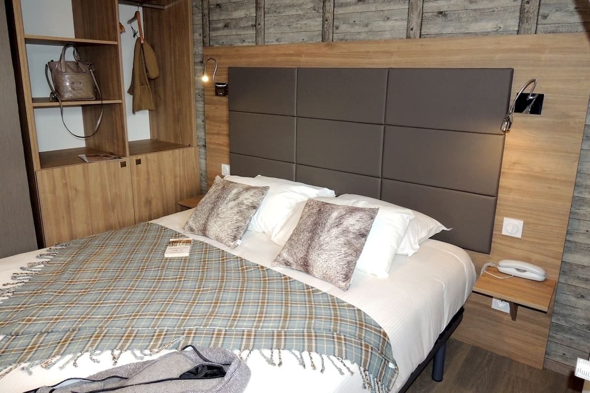 Ein Schlafzimmer mit einem Bett, einem Holzschrank und einem Nachttisch mit einem Telefon.