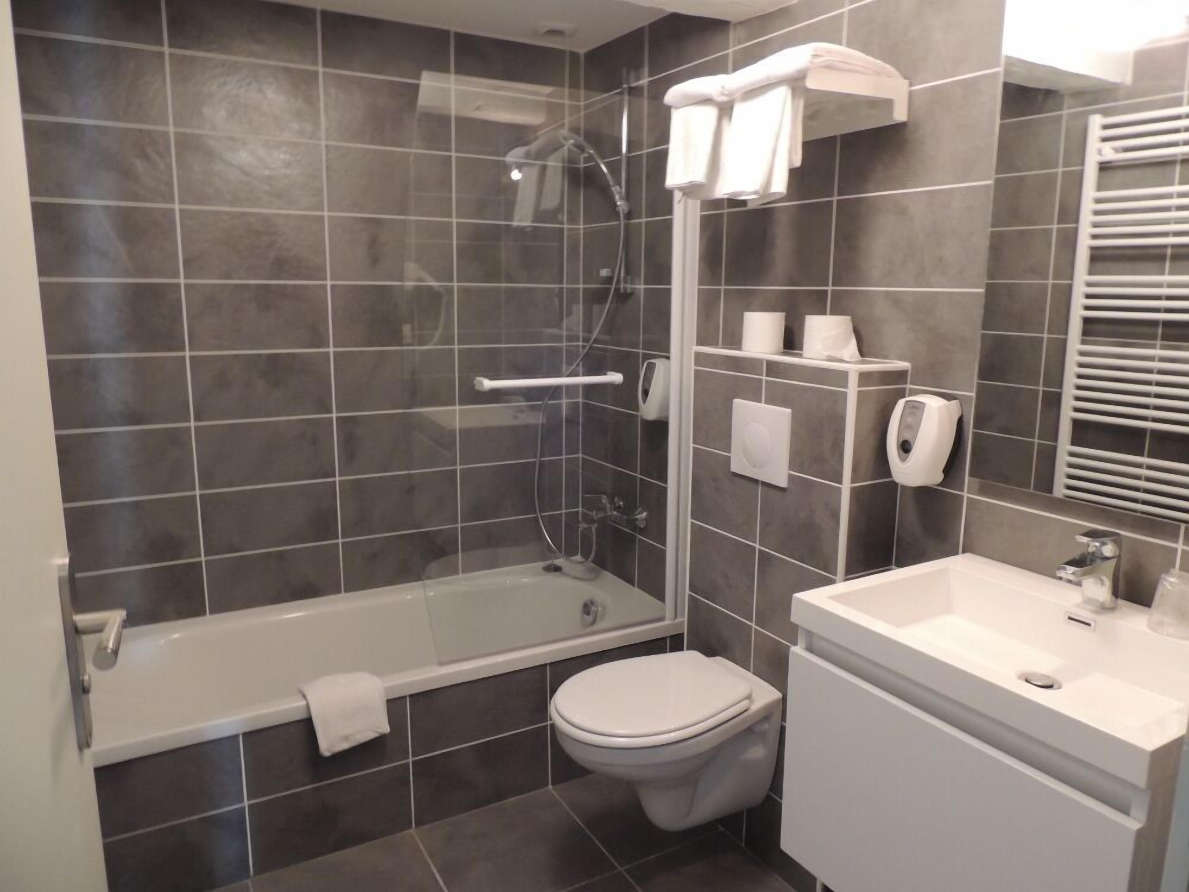 A modern bathroom with a bathtub, toilet, and sink.