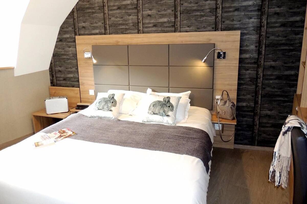Ein Hotelzimmer mit Bett, Nachttisch, Lampe und einem hölzernen Kopfteil.