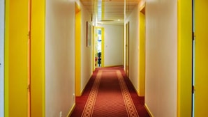 Un pasillo con puertas amarillas, alfombra estampada e iluminación empotrada.