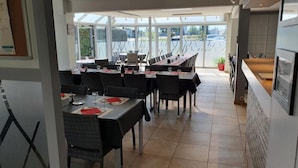 Un restaurante con mesas dispuestas para comer, un amplio ventanal con vistas y una zona de barra.