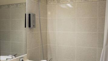 A bathroom with a sink, mirror, shower, and bathtub.