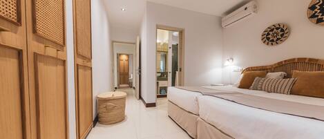 A hotel room with a large bed, a small round table, and a wall-mounted air conditioner.