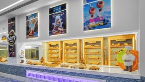 A bakery display area with various baked goods and a chef statue.