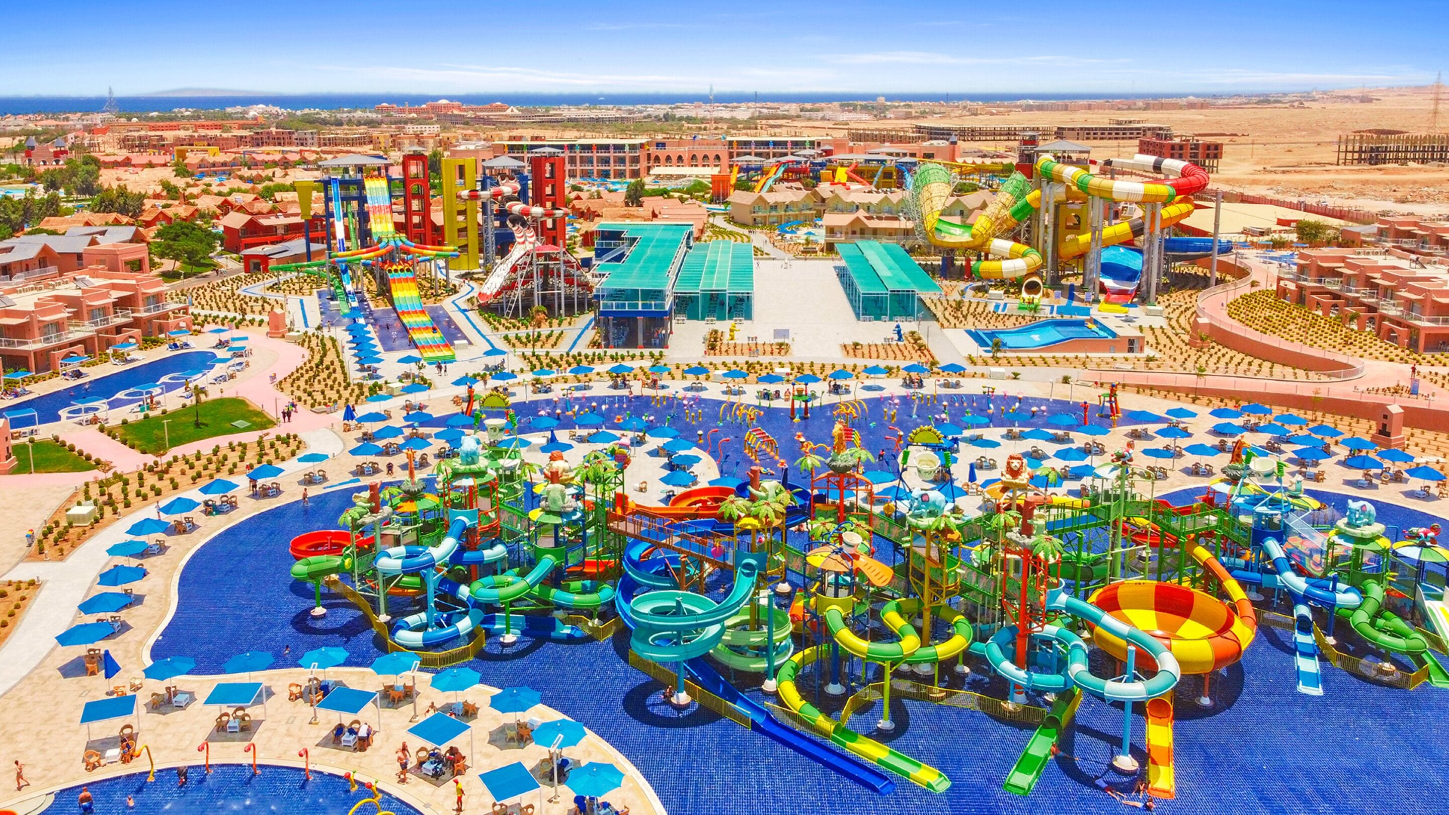 A water park with multiple slides and pools, surrounded by buildings and a clear sky.