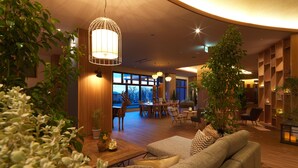 A spacious living area with a wooden floor, a sofa, a dining table with chairs, and a large window offering a view of the outdoors. - Kiki Shiretoko Natural Resort (Shari)