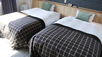 Two single beds with checkered bedspreads, a wooden headboard, a small bedside table, and a wall-mounted clock.