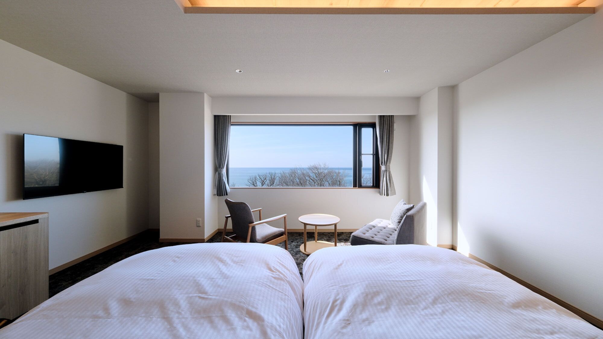 Ein Hotelzimmer mit Bett, Fernseher, Schreibtisch, Stuhl und einem Fenster mit Blick.