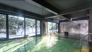 A large indoor swimming pool with a green tiled floor, large windows, and a view of a snowy outdoor area. - Kiki Shiretoko Natural Resort (Shari)