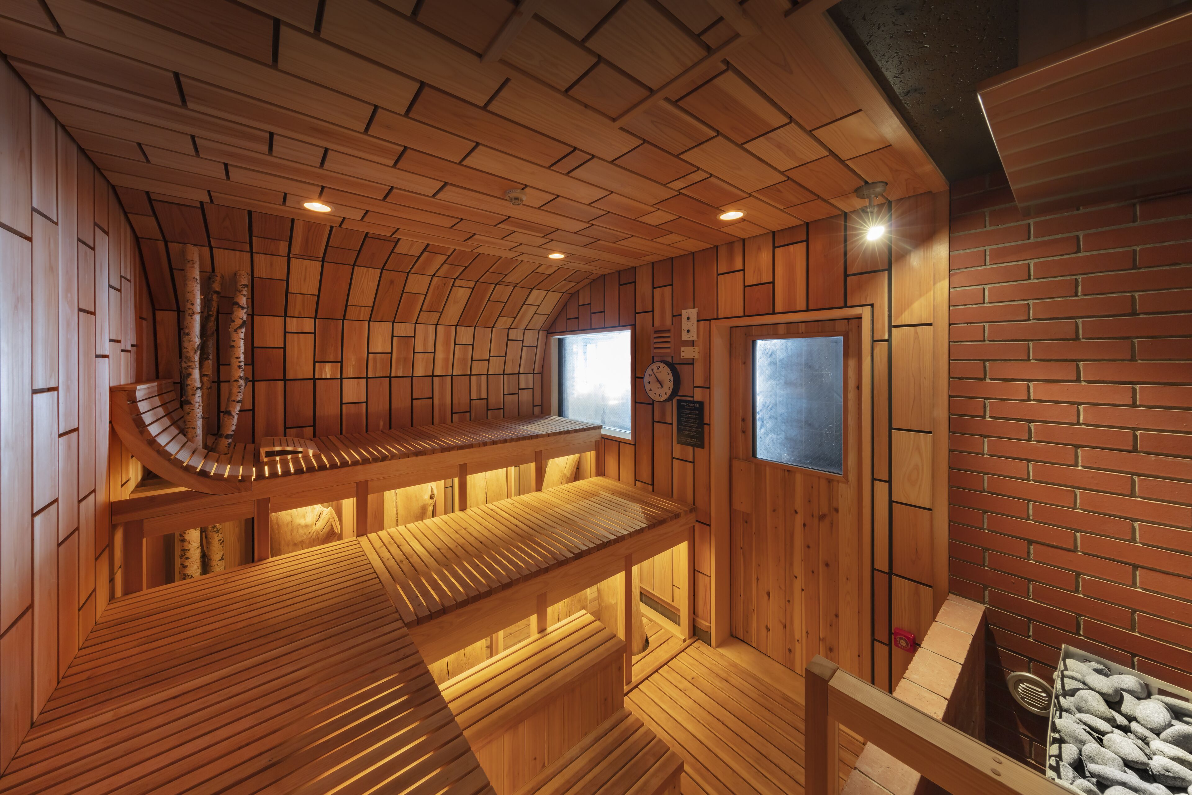Un sauna avec des bancs en bois et un mur en briques.