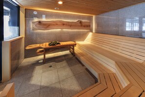 Moderni sauna, jossa on puinen lauteet, kalteva katto ja kiviseinä.