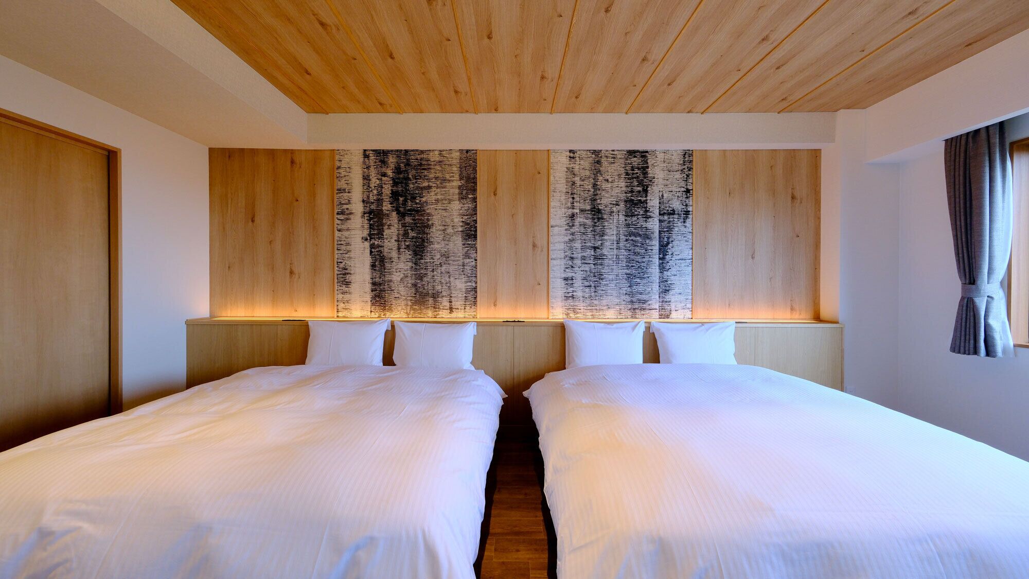 Ein Hotelzimmer mit zwei Betten, Holz-Kopfteilen und einem großen, abstrakten Gemälde.