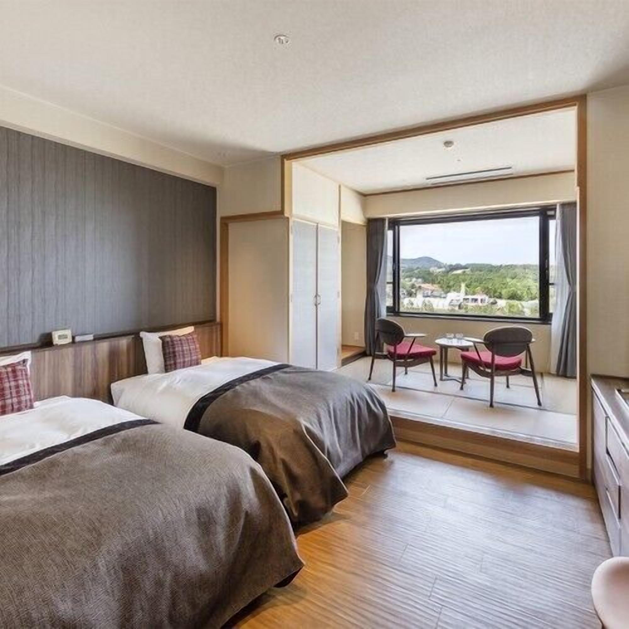 A hotel room with two beds, a balcony with a table and chairs, and a view of the landscape.