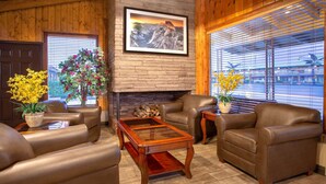 A cozy living room with leather sofas, a wooden coffee table, and a fireplace. - Travelodge by Wyndham Hawthorne (Hawthorne)