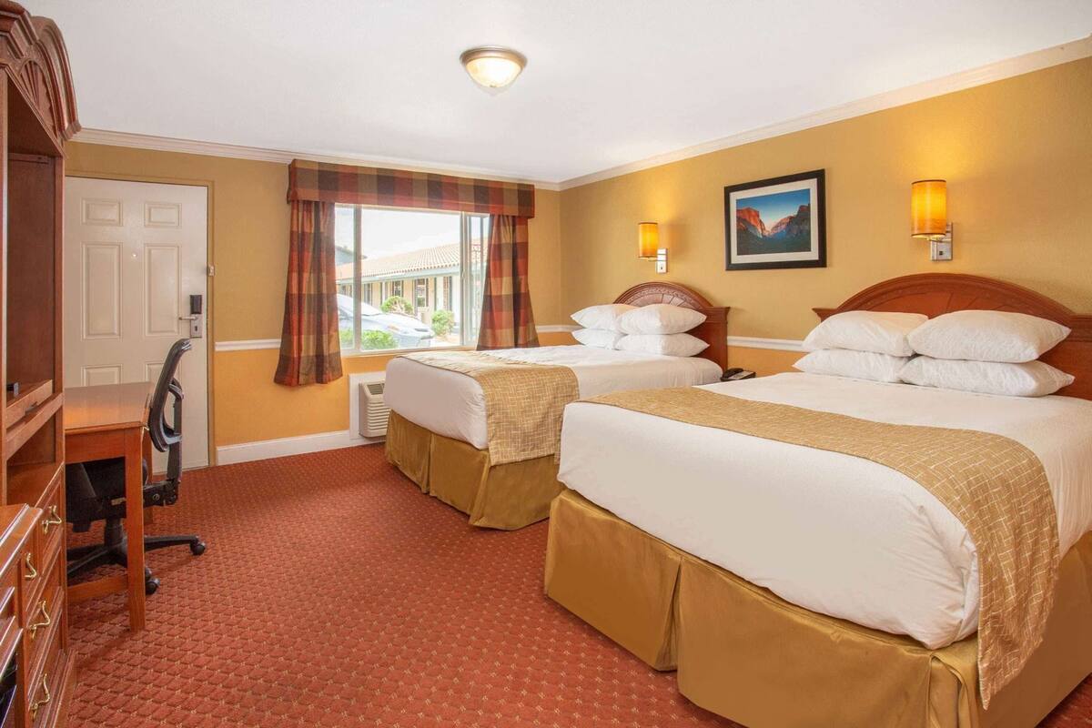 Ett hotellrum med två sängar, ett skrivbord och en stol.