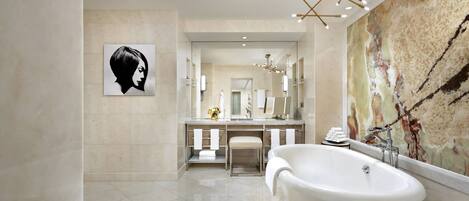 Un baño moderno con una bañera independiente, un espejo grande y una pared de mármol.