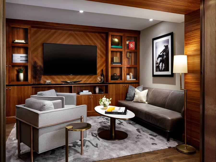 Una sala de estar moderna con un televisor de pantalla plana grande, un sofá, una mesa de centro y una estantería.