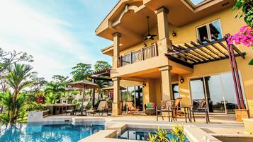 A two-story house with a large balcony, a swimming pool, and outdoor furniture.