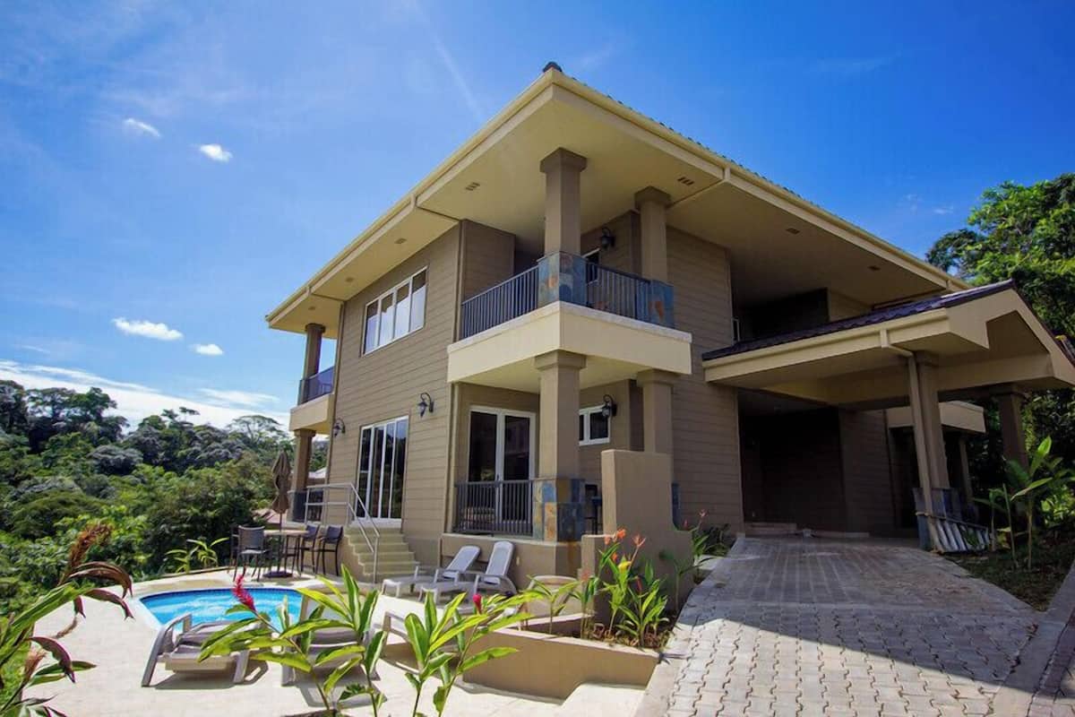 Une maison à deux étages dotée d’une piscine, d’un espace salon extérieur et d’un patio couvert.