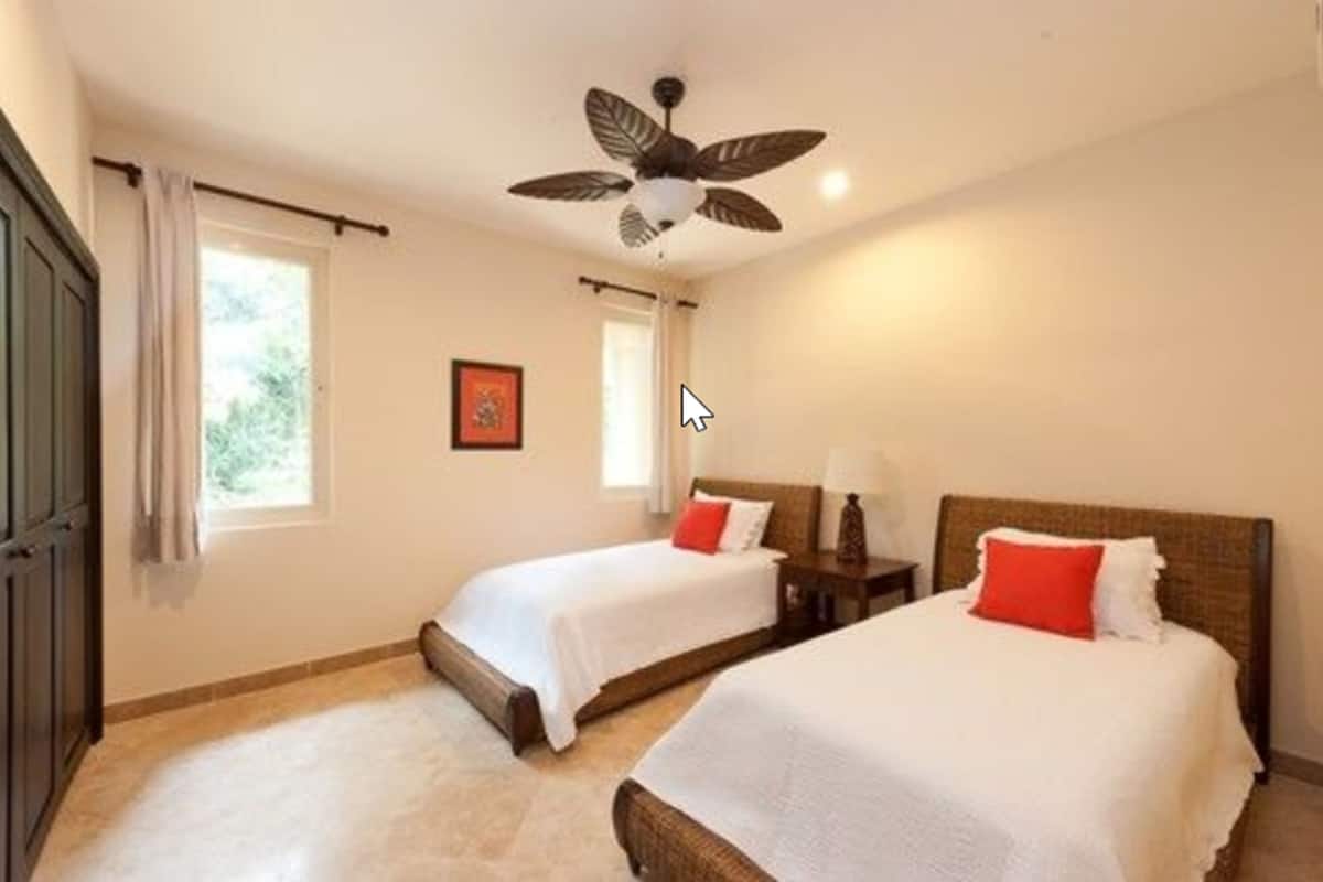 Une chambre d’hôtel avec deux lits, un ventilateur de plafond et une fenêtre avec des rideaux.