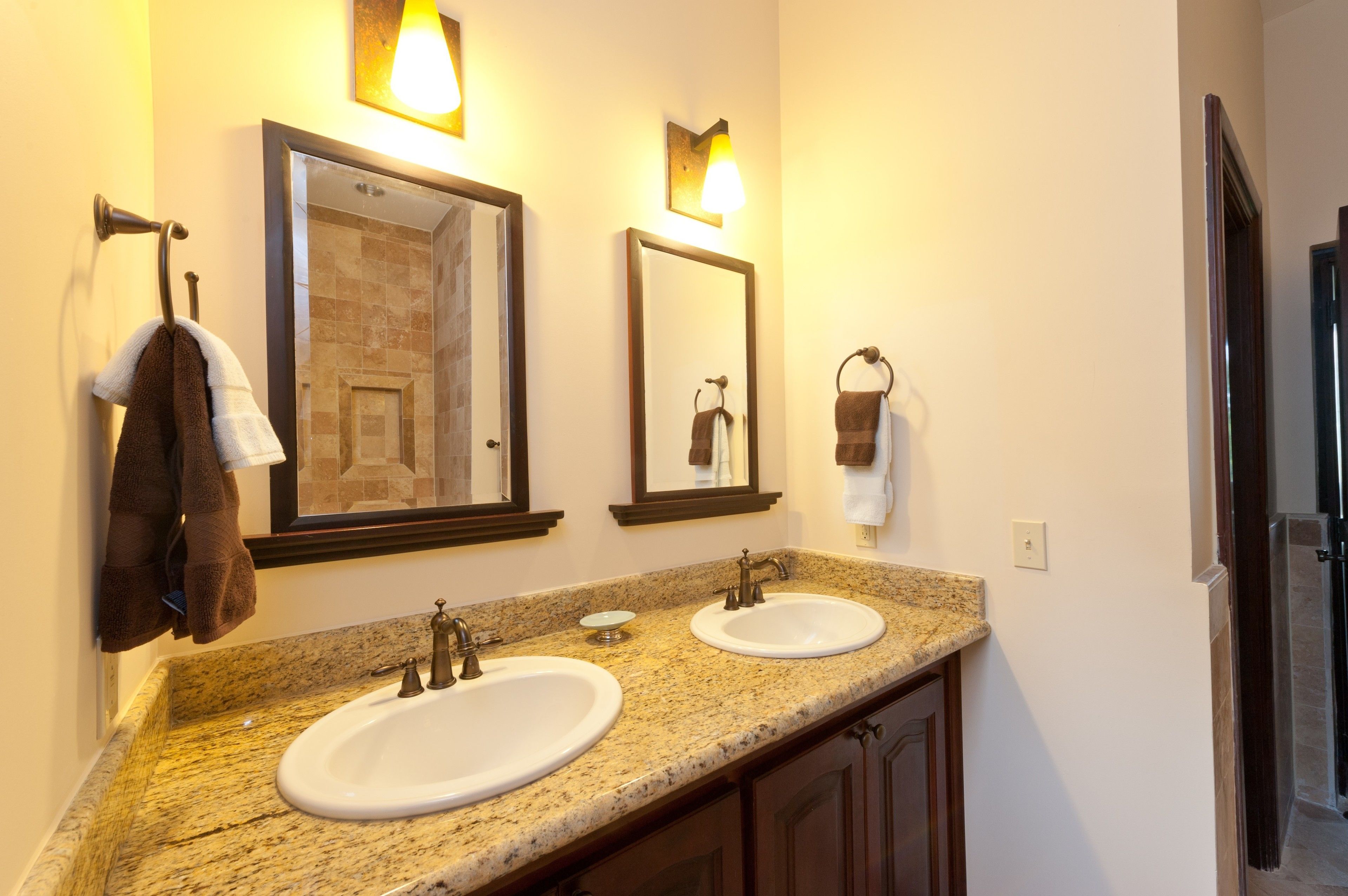 A bathroom with two sinks, a mirror, and towel racks.