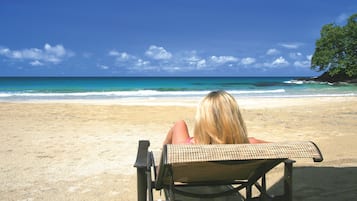 Une chaise de plage donnant sur l’océan, sous un ciel dégagé.
