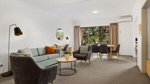 Ein modernes Wohnzimmer mit einer Couch, Sesseln, einem Couchtisch und einem Essbereich mit Stühlen und einem Tisch.