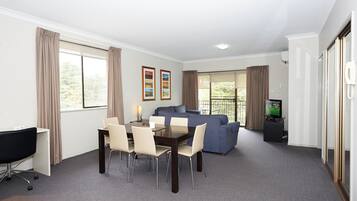 A room with a dining table, chairs, a sofa, a TV, and a desk.