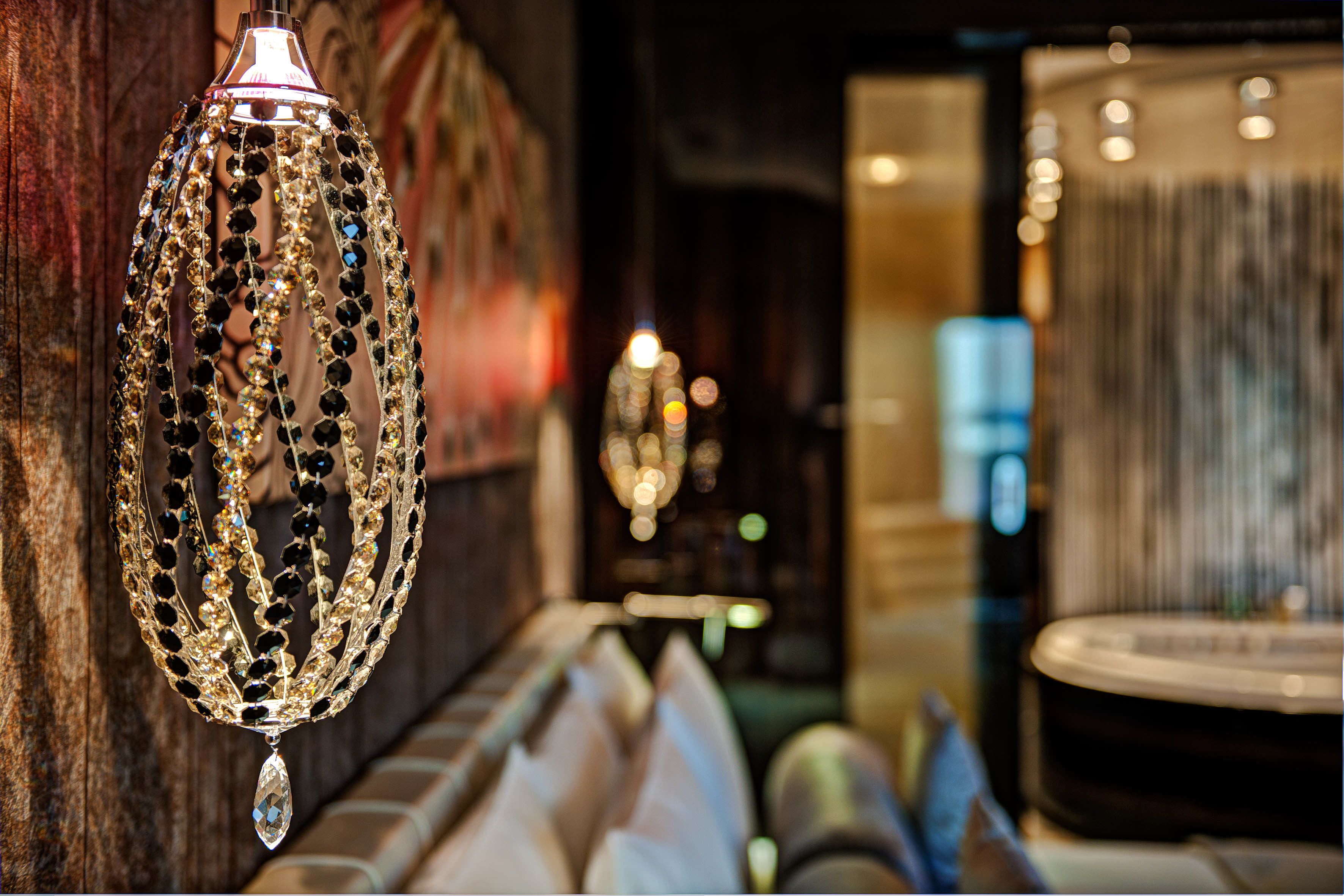 A chandelier with multiple strands of beads and a teardrop-shaped crystal hanging from a wall.