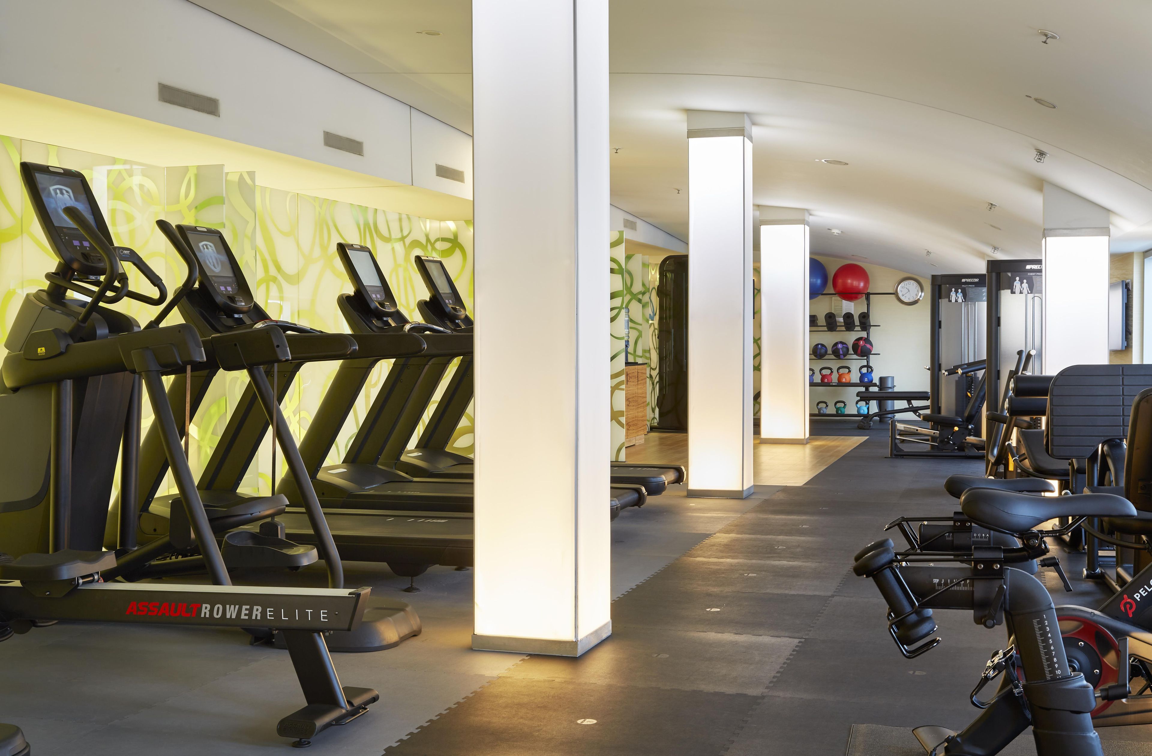 Et fitnessrum med løbebånd, romaskine og håndvægte.