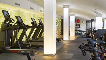 Et fitnessrum med løbebånd, romaskine og håndvægte.