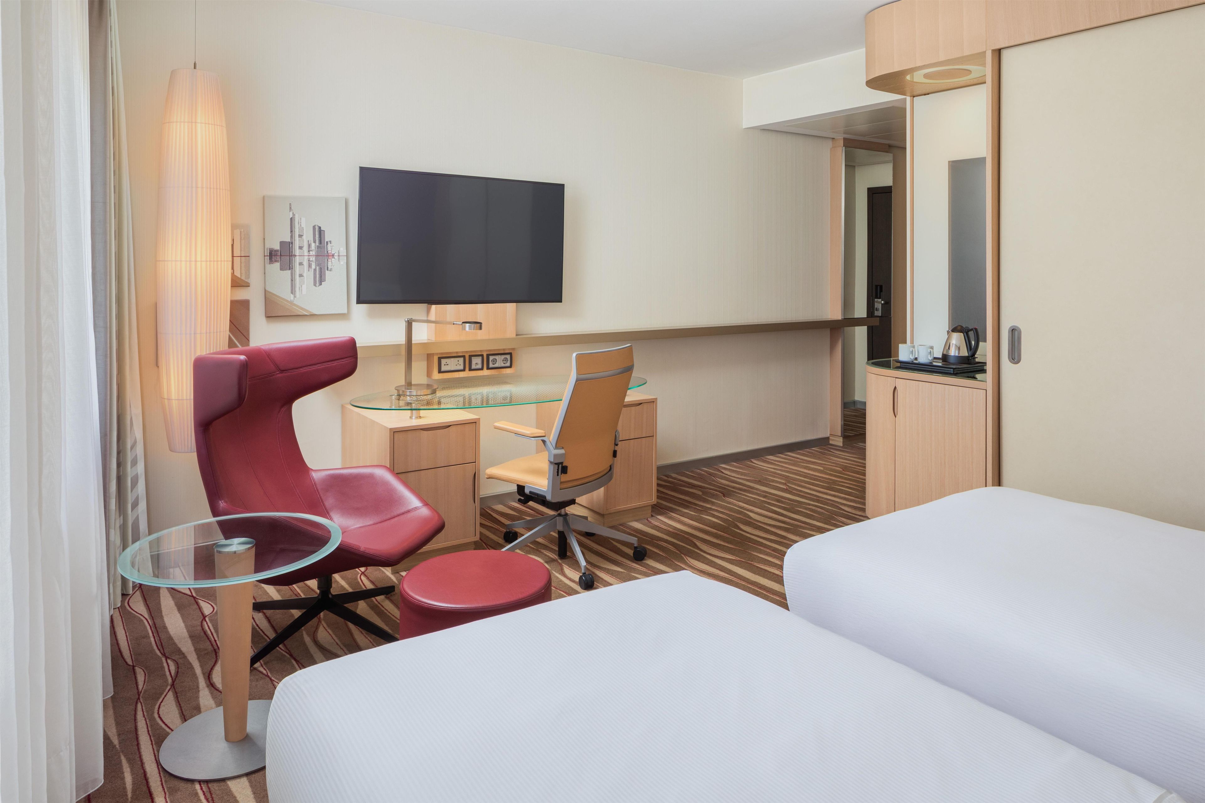 A hotel room with a bed, a desk with a chair, a television, and a mirror.