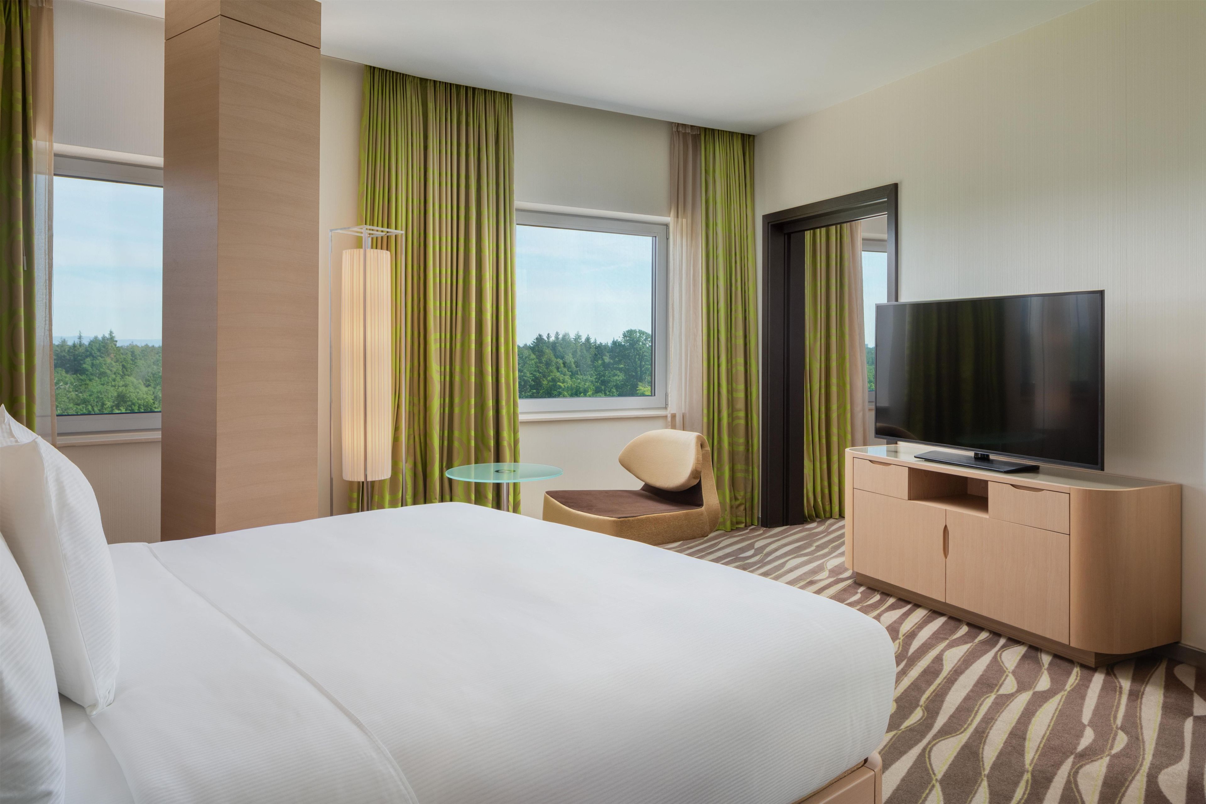 A hotel room with a bed, a television, a desk, and a chair.