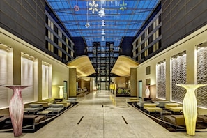 A modern hotel lobby with a high ceiling, glass panels, and contemporary furnishings.
