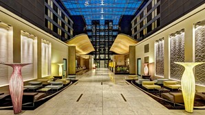 A spacious lobby with a high ceiling, modern lighting, and large vases. - Hilton Frankfurt Airport (Frankfurt)